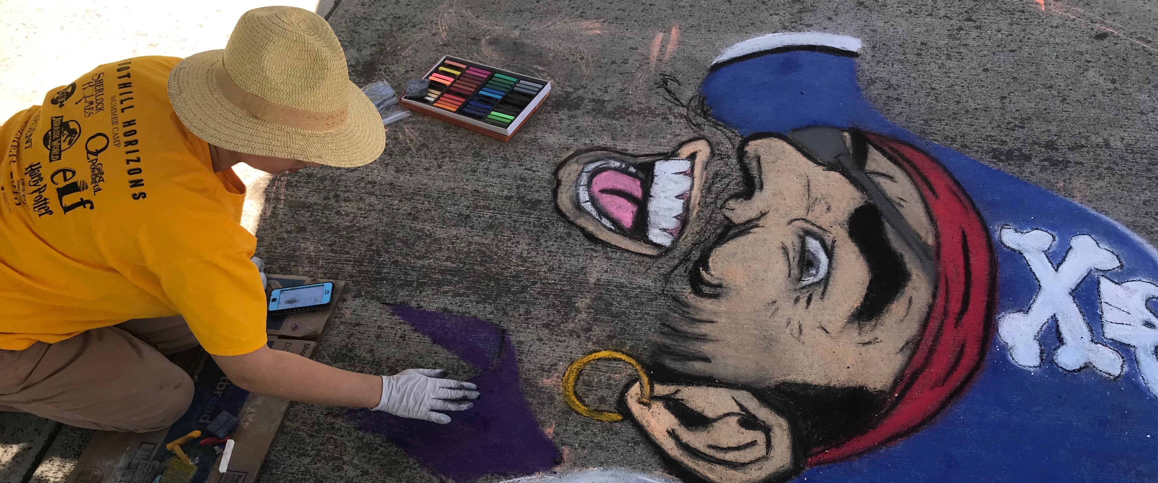 Artist Creating a Sidewalk Chalk Drawing of a Pirate