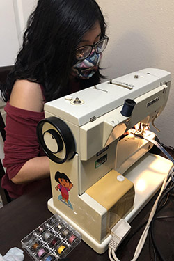 Rubidia Cortez uses a sewing machine to assemble a protective mask