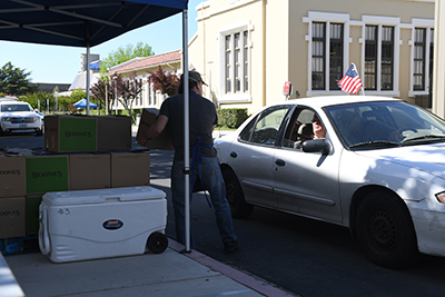 An MJC employee pulls a box off a stack of food boxes.